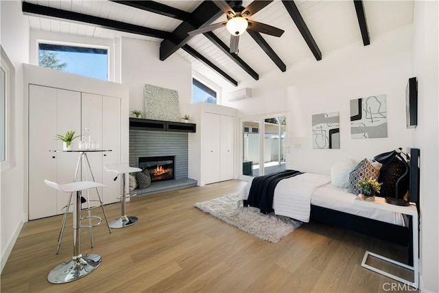 bedroom featuring high vaulted ceiling, beamed ceiling, a tile fireplace, and wood finished floors