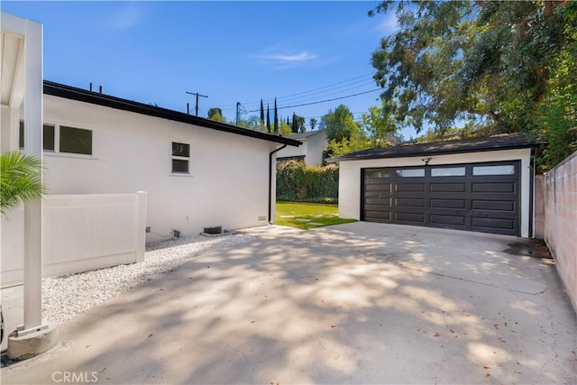 view of side of home with a detached garage, stucco siding, and an outbuilding