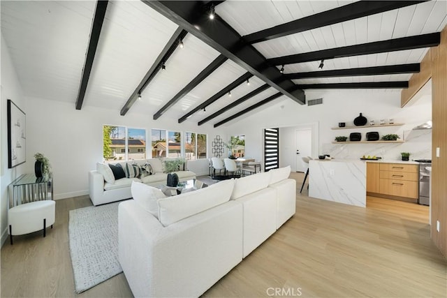 living area with track lighting, visible vents, lofted ceiling with beams, baseboards, and light wood-type flooring