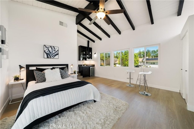 bedroom with lofted ceiling with beams, wood finished floors, and baseboards