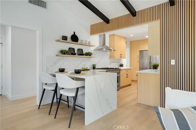 kitchen featuring light brown cabinetry, visible vents, wall chimney exhaust hood, and appliances with stainless steel finishes