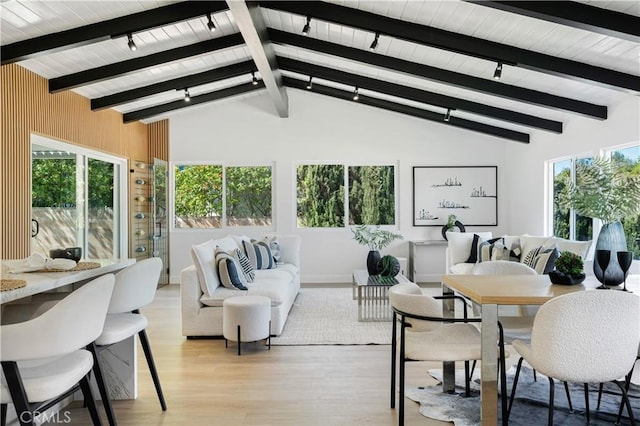 living area with light wood finished floors, track lighting, vaulted ceiling with beams, and a healthy amount of sunlight