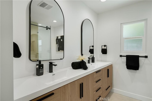 bathroom with double vanity, visible vents, an enclosed shower, baseboards, and recessed lighting