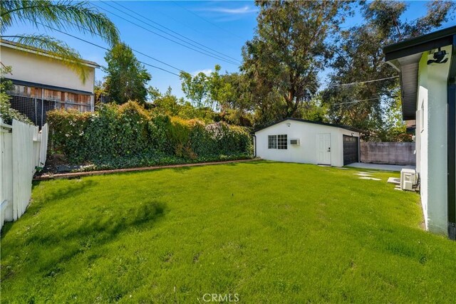 view of yard featuring a detached garage, a fenced backyard, and an outdoor structure