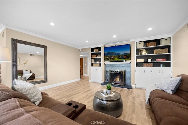 living area featuring baseboards, crown molding, a tile fireplace, and light wood-style flooring