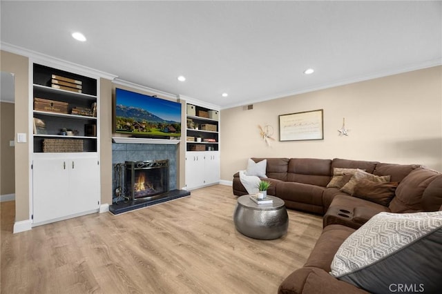 living area with wood finished floors, a fireplace, recessed lighting, and ornamental molding