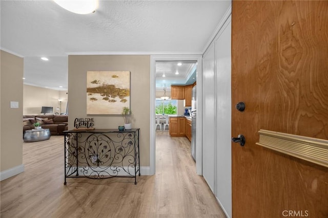 hall featuring recessed lighting, light wood-style floors, crown molding, and baseboards