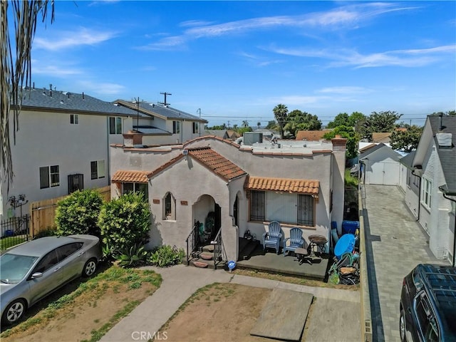 view of front of home featuring stucco siding, fence, a tile roof, and a patio