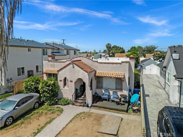 view of front of home featuring fence, a tiled roof, stucco siding, and a residential view
