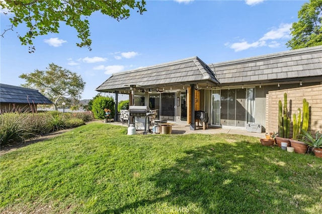 back of property with a lawn, a patio, and mansard roof