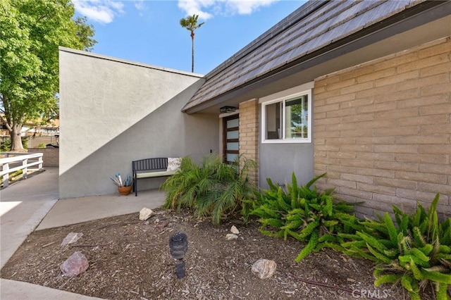 view of home's exterior featuring brick siding, stucco siding, and a patio area