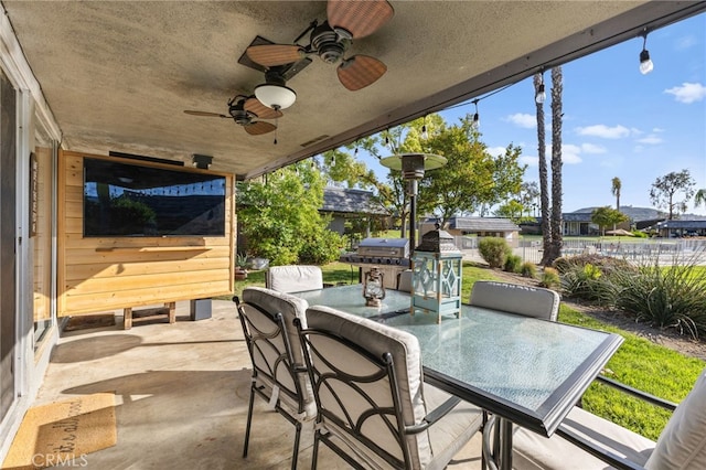 view of patio featuring fence, outdoor dining space, area for grilling, and ceiling fan