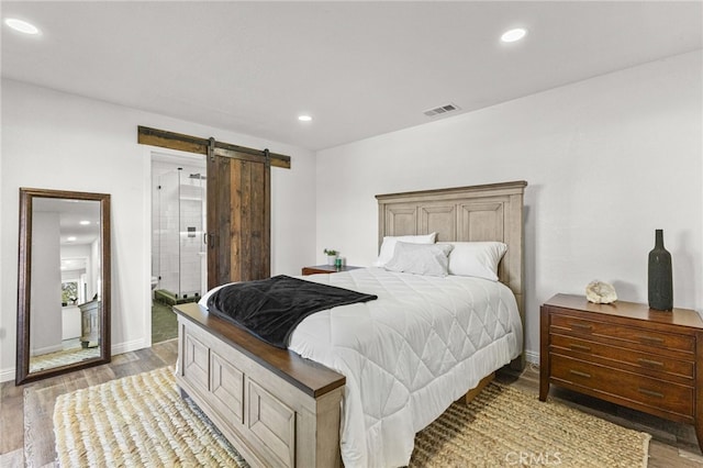 bedroom with recessed lighting, visible vents, a barn door, and light wood-type flooring