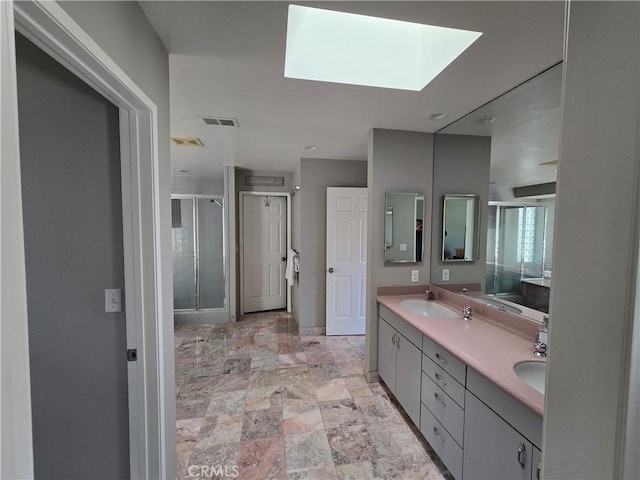 bathroom with a shower stall, double vanity, visible vents, a sink, and a skylight