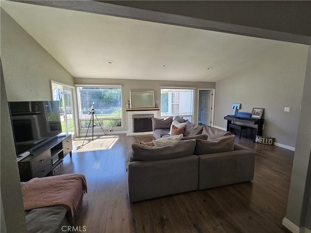 living area featuring wood-type flooring, lofted ceiling, a brick fireplace, and baseboards