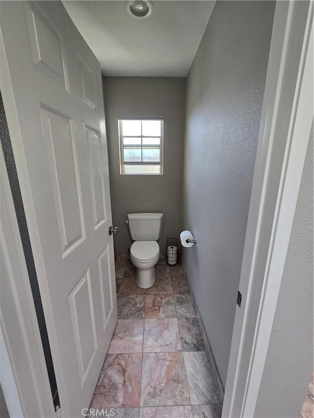 bathroom with marble finish floor and toilet