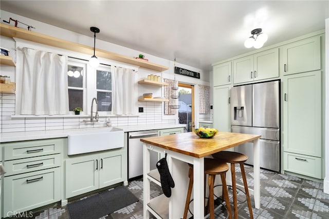 kitchen with open shelves, appliances with stainless steel finishes, green cabinetry, and a sink