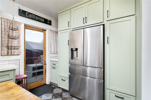 kitchen featuring dark floors, light countertops, green cabinetry, and stainless steel fridge with ice dispenser