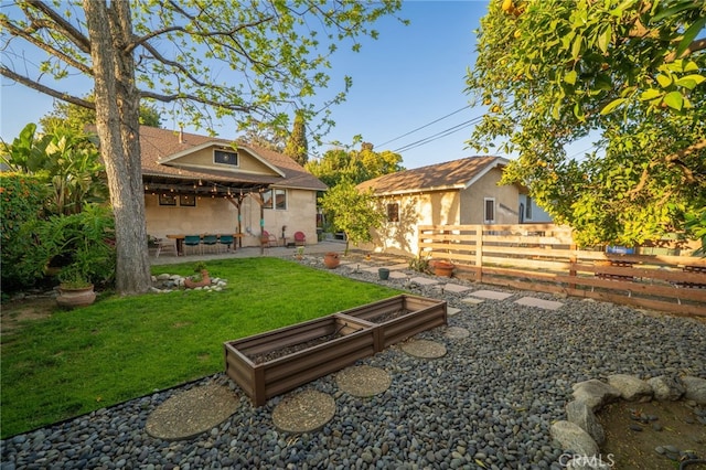 exterior space featuring a lawn, fence, a patio area, and a vegetable garden