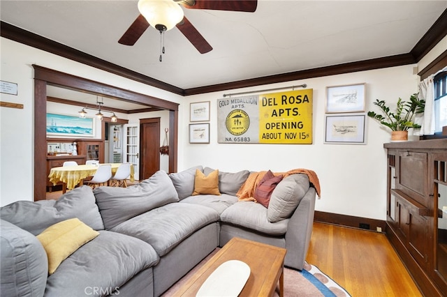 living area with a ceiling fan, baseboards, crown molding, and wood finished floors