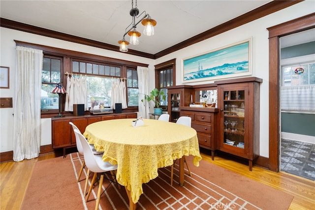 dining area featuring light wood-style flooring, baseboards, and crown molding