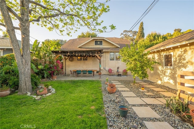 back of house featuring a pergola, fence, a lawn, a patio, and stucco siding