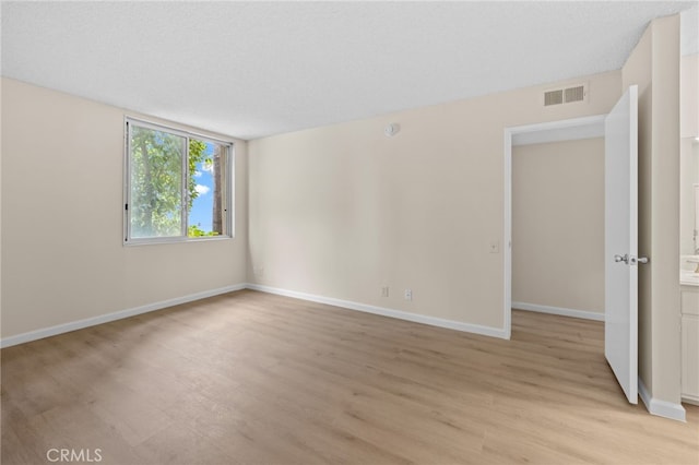 empty room featuring baseboards, visible vents, and light wood-style flooring