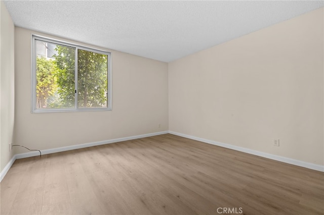 empty room featuring a textured ceiling, baseboards, and wood finished floors