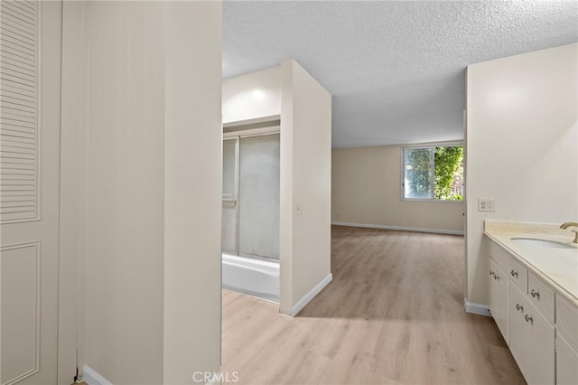 bathroom featuring baseboards, a textured ceiling, wood finished floors, and vanity
