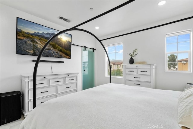 bedroom with recessed lighting, visible vents, and a barn door