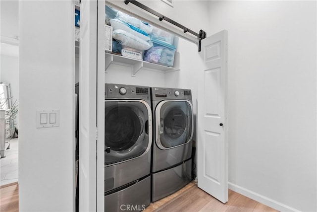 clothes washing area with baseboards, laundry area, light wood-style flooring, and independent washer and dryer