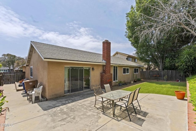 rear view of property with a patio area, a shingled roof, stucco siding, a lawn, and a fenced backyard