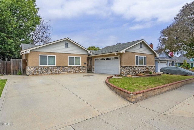 view of front of house with stucco siding, fence, a garage, driveway, and stone siding