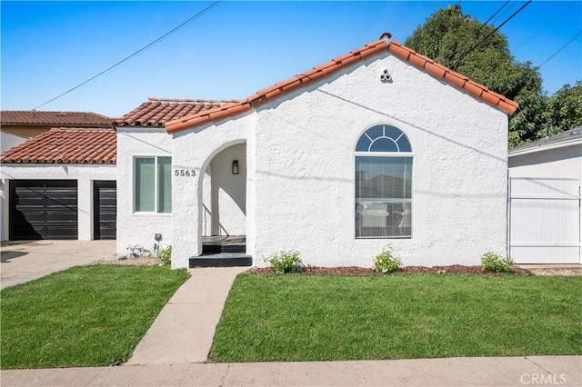 mediterranean / spanish-style house featuring a tiled roof, concrete driveway, a garage, a front yard, and stucco siding