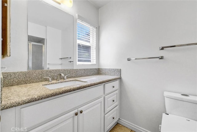 bathroom featuring a shower stall, toilet, vanity, and baseboards
