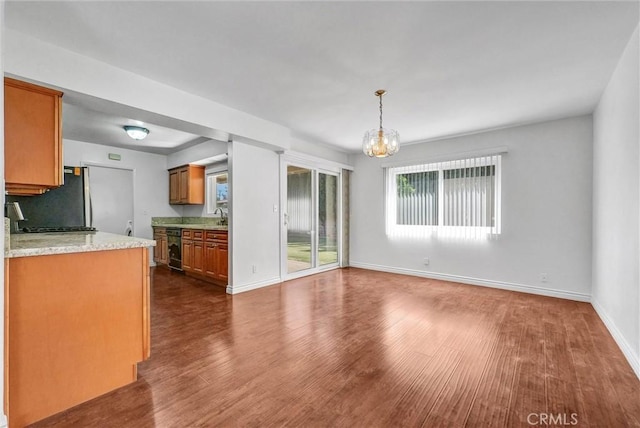 kitchen featuring a sink, dark wood finished floors, baseboards, an inviting chandelier, and brown cabinetry