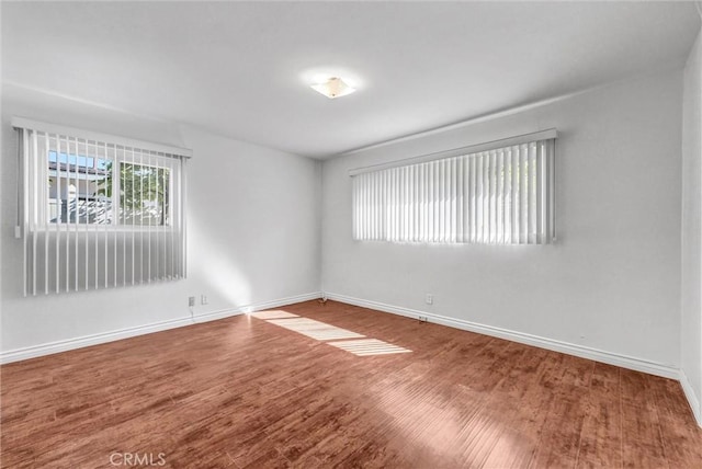 empty room featuring wood finished floors and baseboards