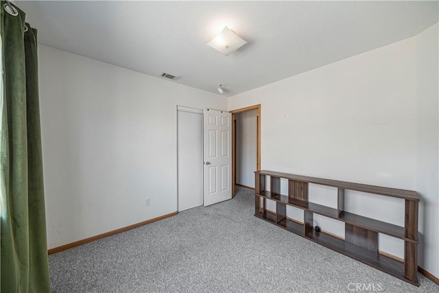 spare room with carpet floors, baseboards, and visible vents