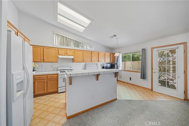 kitchen featuring white appliances, tile counters, lofted ceiling, and light floors