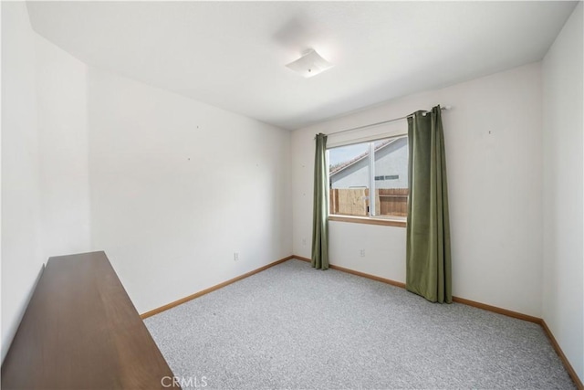 empty room featuring light colored carpet and baseboards
