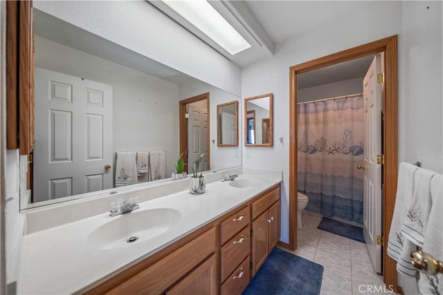 bathroom featuring double vanity, a sink, tile patterned flooring, and toilet
