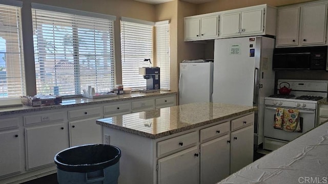 28320 Via Bandita, Menifee, CA 92585 - kitchen with light stone countertops, a center island, white appliances, and white cabinetry