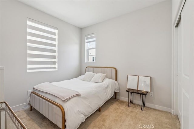 bedroom featuring light carpet, baseboards, and a closet