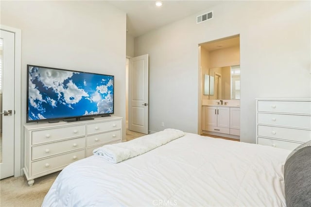 bedroom featuring ensuite bathroom, visible vents, and light colored carpet