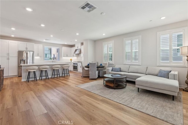 living room featuring light wood finished floors, visible vents, and recessed lighting
