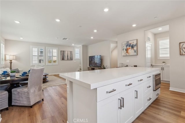 kitchen featuring white cabinets, open floor plan, light wood-style floors, and recessed lighting