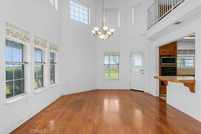 10735 Shasta Blvd, Los Molinos, CA 96055 - interior space featuring wood finished floors, baseboards, a high ceiling, a notable chandelier, and visible vents