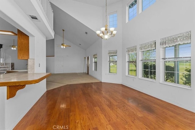 10735 Shasta Blvd, Los Molinos, CA 96055 - unfurnished living room featuring ceiling fan with notable chandelier, wood finished floors, high vaulted ceiling, and visible vents