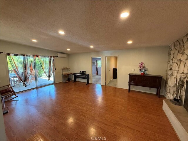 1711 S Washington Ave, Glendora, CA 91740 - workout area featuring a textured ceiling, an AC wall unit, wood finished floors, recessed lighting, and a fireplace