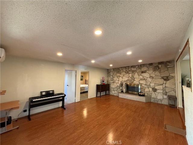 1711 S Washington Ave, Glendora, CA 91740 - living room featuring a textured ceiling, wood finished floors, recessed lighting, a stone fireplace, and a wall mounted AC